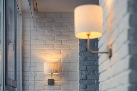 Zwei leuchtende Wandleuchten an weißer Backsteinwand