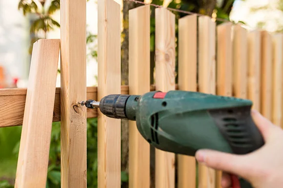 Person baut einen Holzzaun mit Akkuschrauber