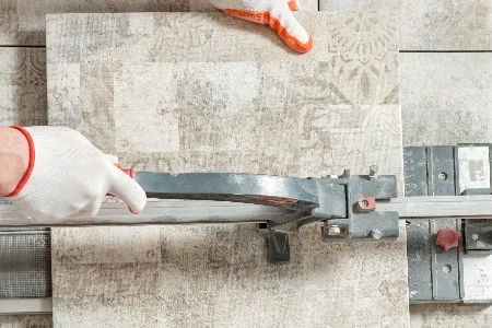 Eine Fliese wird mit einem Fliesenschneider geschnitten