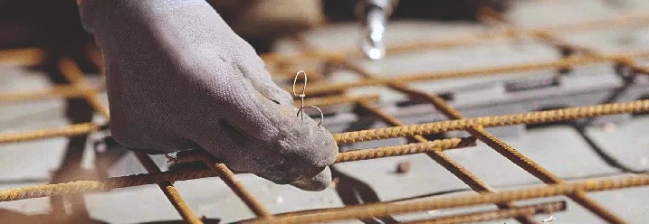 Person befestigt Metallgitter mit Bindedraht.