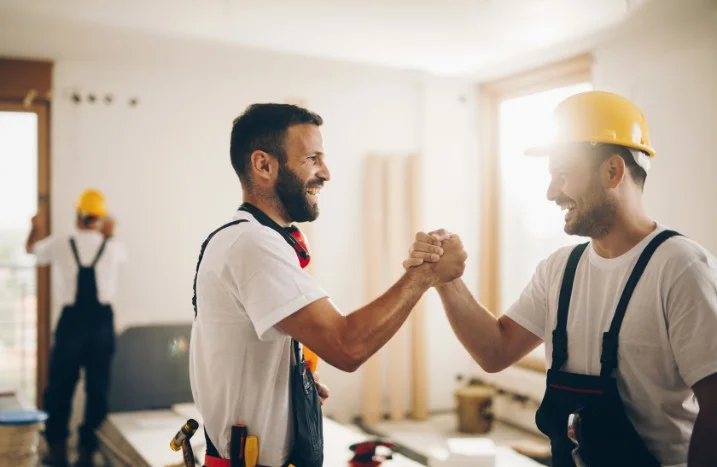 Zwei Personen in Arbeitskleidung geben sich die Hand