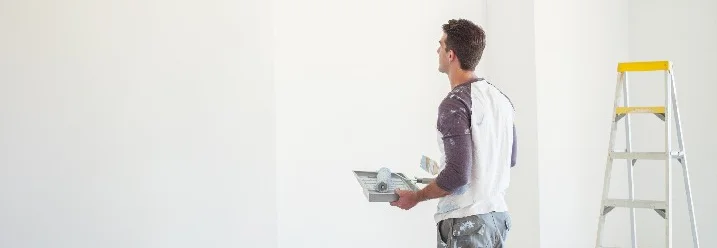 Person beim Streichen einer Wand mit Farbrolle
