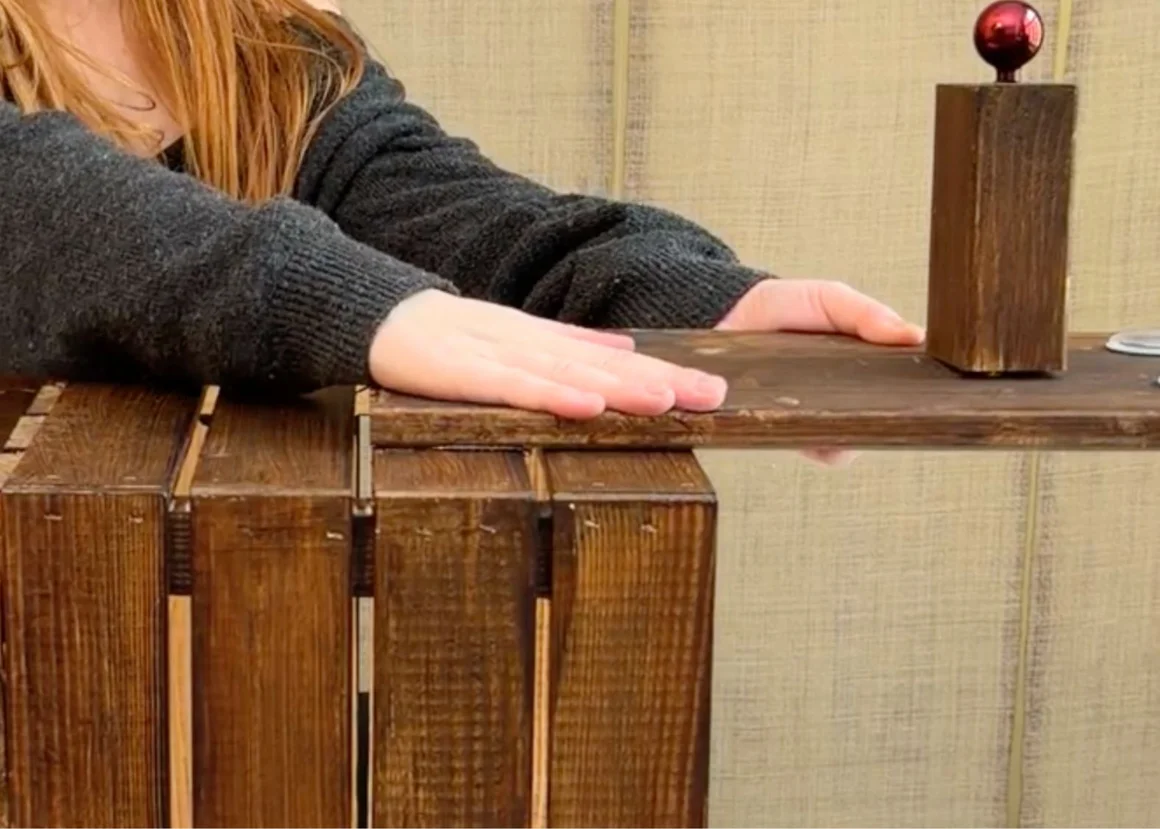 Eine Person präsentiert ein selbstgebautes Möbelstück aus Holz.