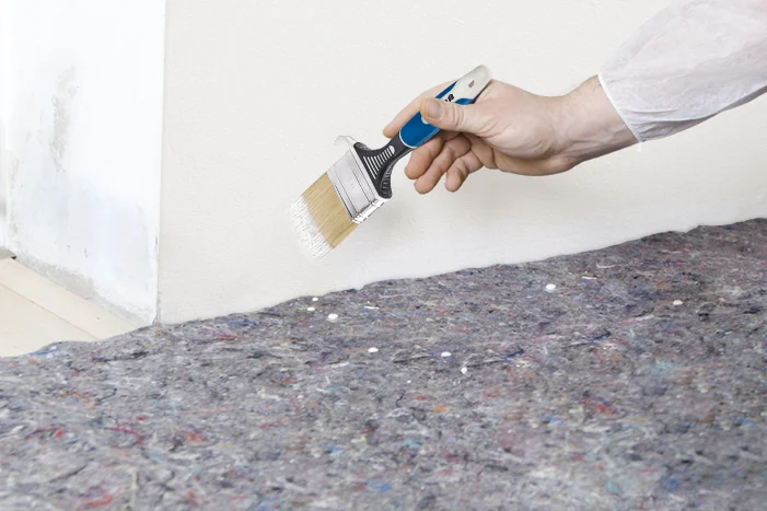 Hand hält Pinsel über grauer Unterlage