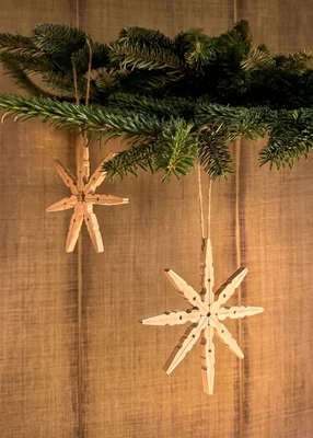 Weihnachtssterne aus Wäscheklammern hängen an einem Tannenzweig