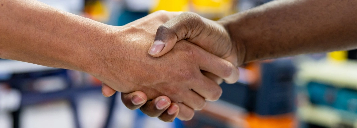 Zwei Menschen geben sich in einem Baumarkt die Hand
