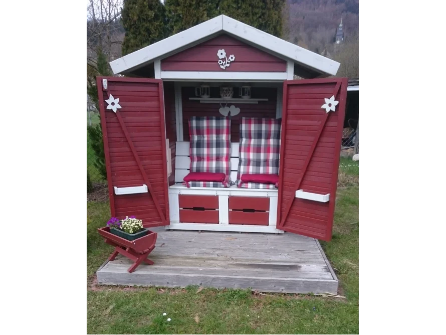 Kleines rotes Gartenhaus mit geöffneten Türen