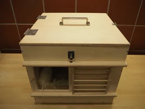 Eine Transportbox aus Holz mit einem flauschigen Tier darin.