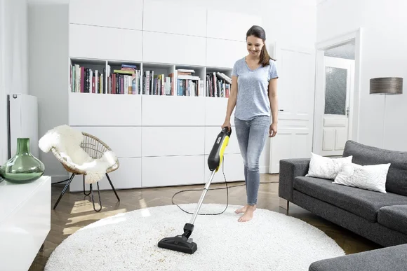 Person saugt mit einem Stabstaubsauger
