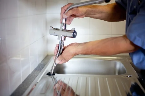 Person montiert einen Wasserhahn.