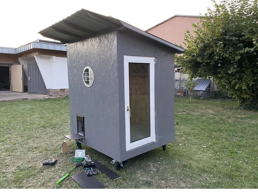 Grau gestrichenes Gartenhaus mit Rädern