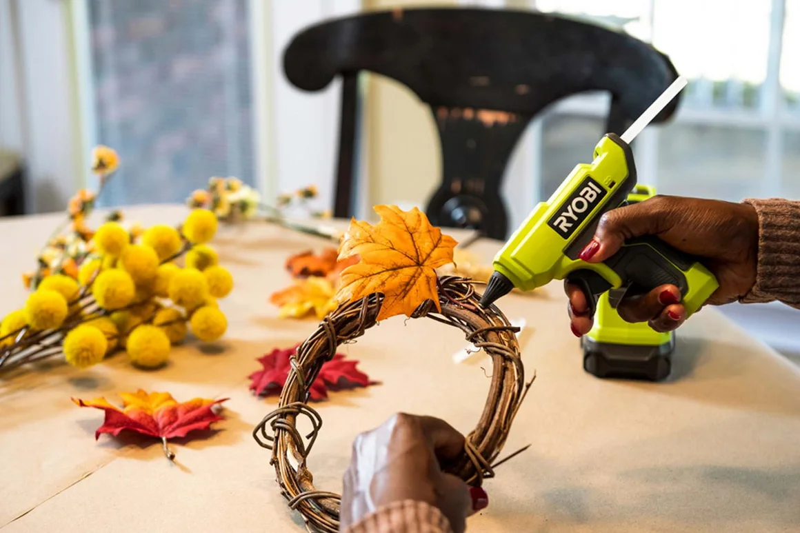 Person klebt Herbstlaub auf Kranz