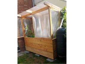 Kleines Gewächshaus aus Holz mit angeschlossener Regentonne