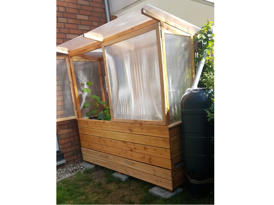 Kleines Gewächshaus aus Holz mit angeschlossener Regentonne