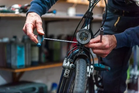 Person montiert Fahrradlampe mit Werkzeug.