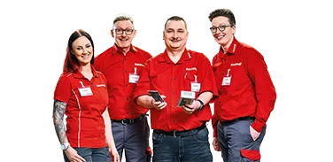 Vier Mitarbeitende in roter Arbeitskleidung lächeln in die Kamera.