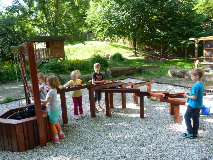 Kinder spielen mit einer Murmelbahn im Garten