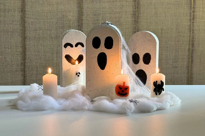 Gebastelte Halloween-Geister aus Stein mit Kerzen und Spinnennetzen.