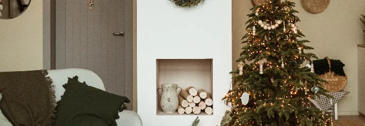 Weihnachtlich dekoriertes Wohnzimmer mit Tannenbaum und Kamin.