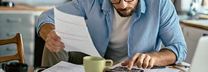 Person berechnet Finanzen mit Taschenrechner