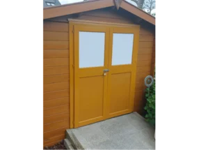 Gelbes Gartenhaus mit weißen Fenstern