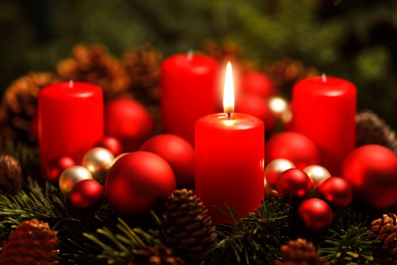 Adventskranz mit einer brennenden roten Kerze, Kugeln und Tannenzapfen.