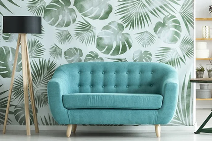 Türkises Sofa vor einer Wand mit Palmblatt-Muster