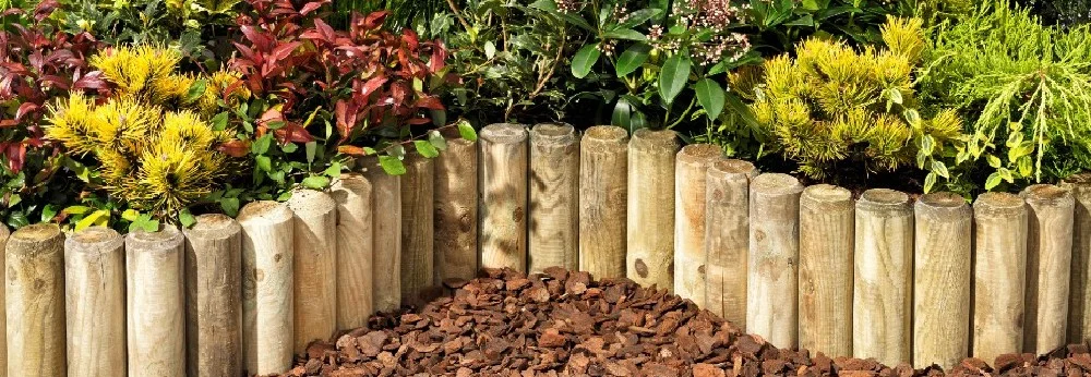 Holzpfosten als Beetumrandung im Garten