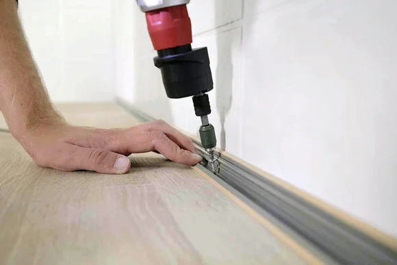 Person verschraubt eine Metallschiene auf einer Arbeitsplatte