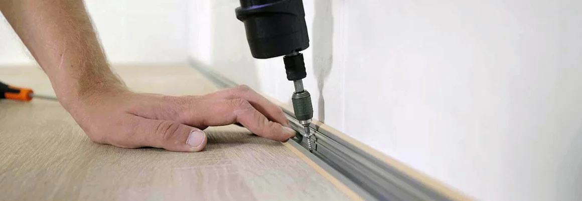 Person verschraubt eine Metallschiene auf einer Arbeitsplatte