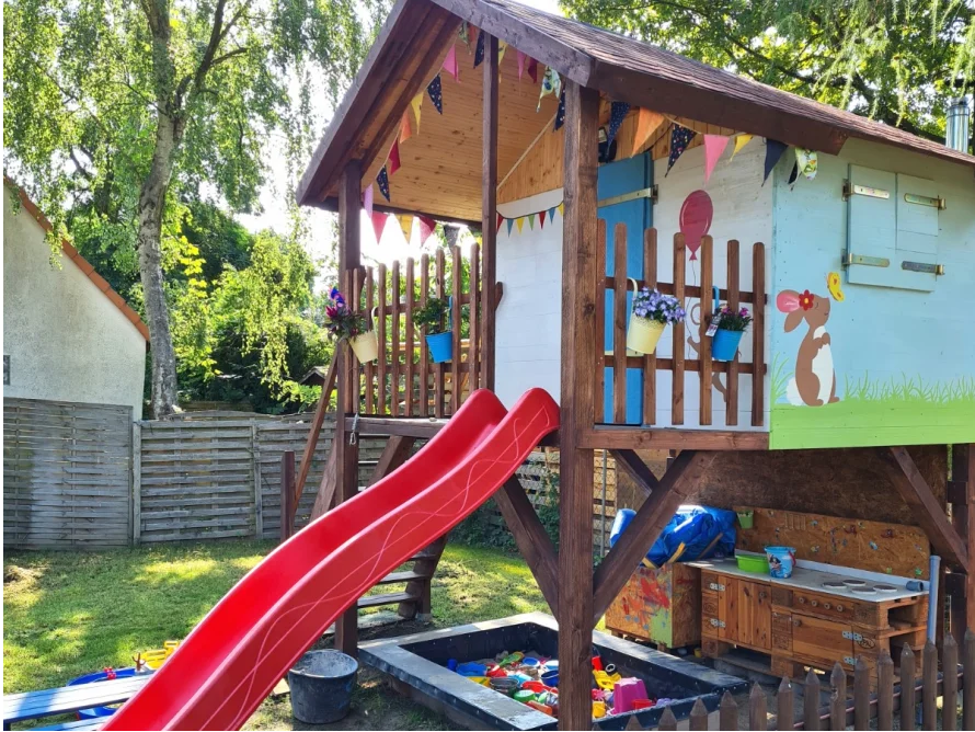 Ein buntes Spielhaus aus Holz mit einer Rutsche.