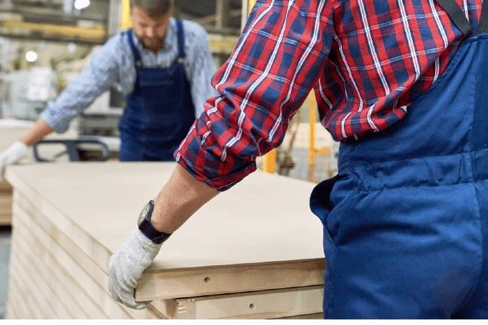 Zwei Personen tragen eine Holzplatte