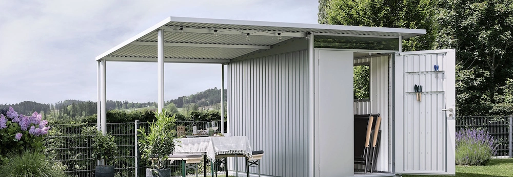 Ein Biohort Gewächshaus mit montiertem Seitendach steht in einem Garten