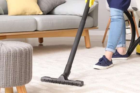 Person saugt Teppich mit Staubsauger