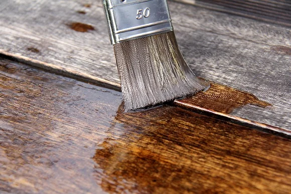 Pinsel trägt Lasur auf Holz auf