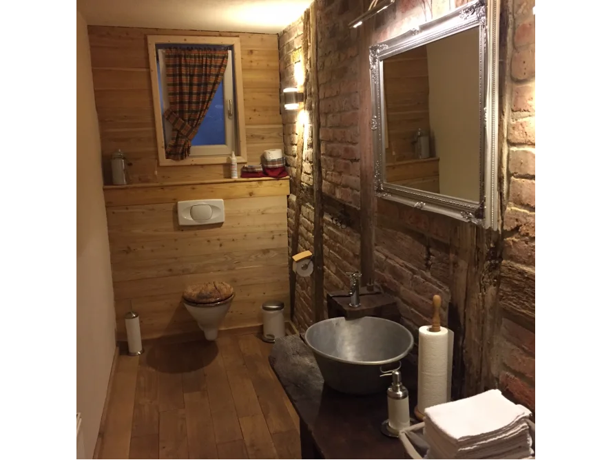 Rustikales Badezimmer mit Holzwänden und Ziegelmauer.