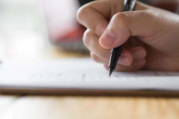 Hand schreibt mit Stift auf Papier
