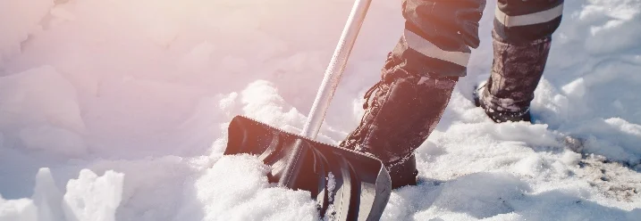 Person räumt Schnee mit Schneeschaufel