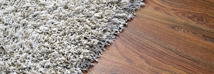 Heller Teppich auf dunklem Holzboden