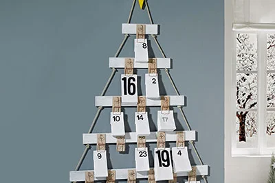 Ein selbstgebauter Adventskalender in Form eines Tannenbaums an der Wand.
