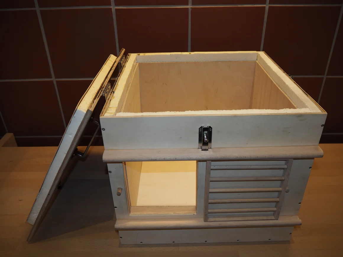 Eine geöffnete, isolierte Holzkiste mit Lüftungsschlitzen und Beleuchtung.