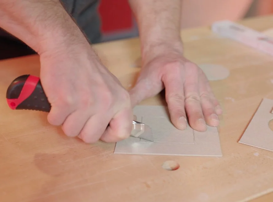 Hände schneiden Pappe mit Cuttermesser