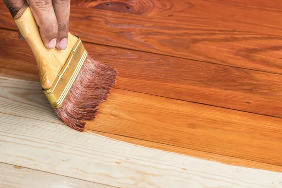 Person streicht Holz braun an