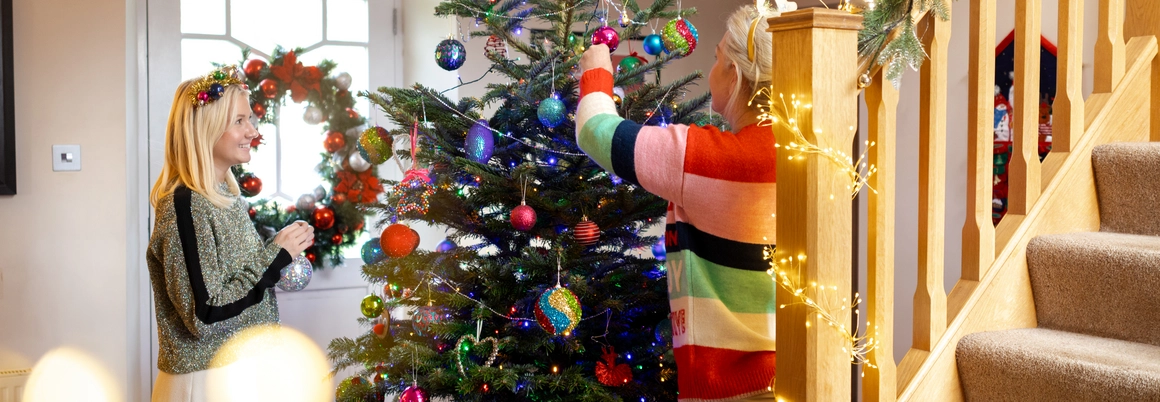 Zwei Personen schmücken gemeinsam einen Weihnachtsbaum.