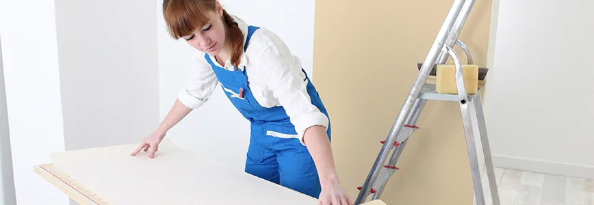 Person beim Zuschneiden von Tapete