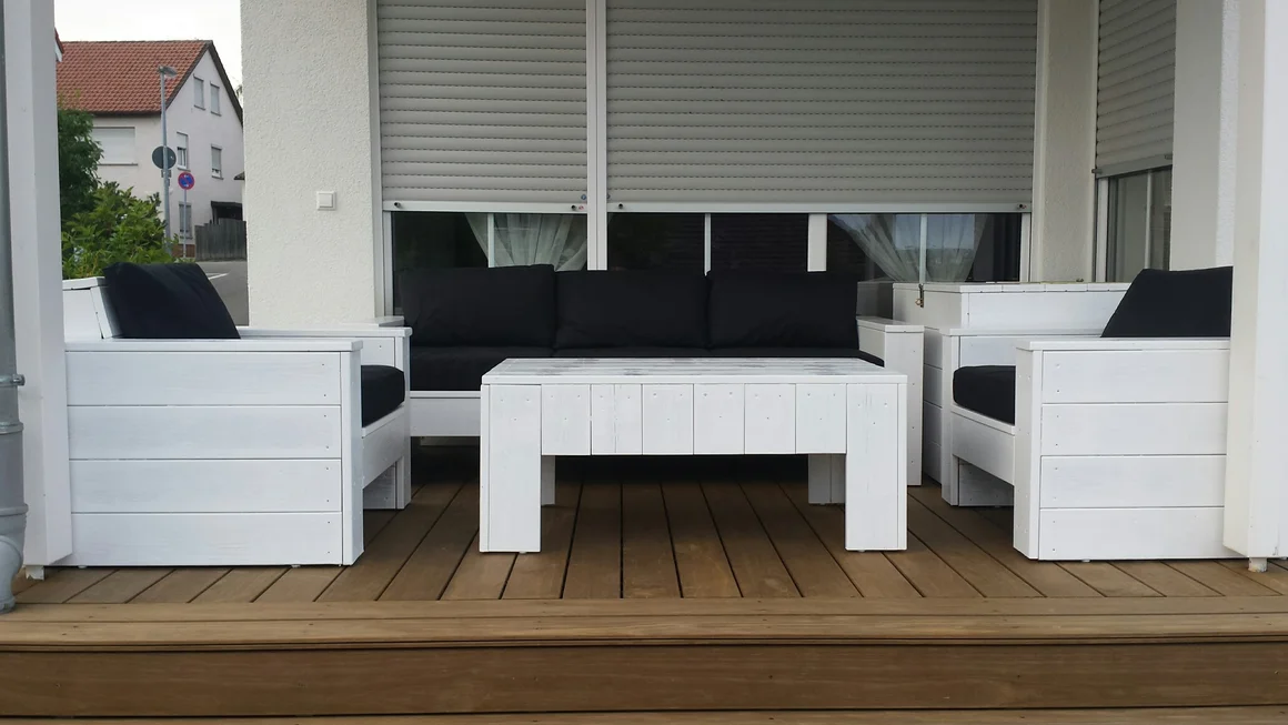 Weiße Gartenmöbel auf einer Holzterrasse