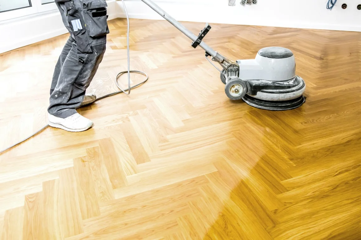Person schleift Holzboden mit Maschine