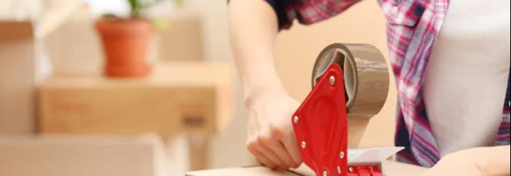 Person verklebt Karton mit Paketklebeband.