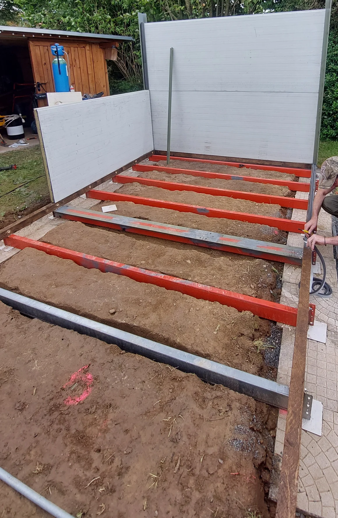 Eine Person baut die Unterkonstruktion für eine Terrasse im Garten.