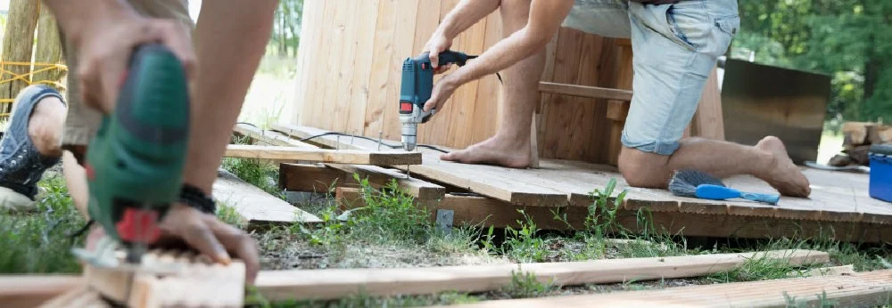 Zwei Personen bauen ein Gartenhaus aus Holz